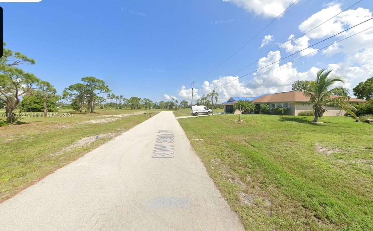 A paved road leads toward a single-story house with a lawn and scattered trees — 4309 NW 36 th PL, Cape Coral FL 33993, CAPE CORAL, FL