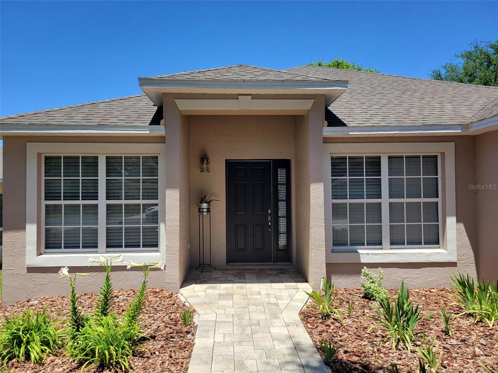 The exterior of a single-story house features a dark front door and a stone walkway — 2160 ADDISON AVENUE, CLERMONT, FL