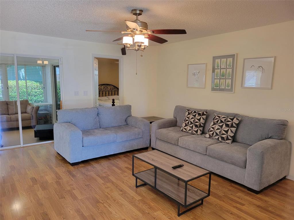A living room features two gray sofas, a wood coffee table, and hardwood flooring — 2160 ADDISON AVENUE, CLERMONT, FL