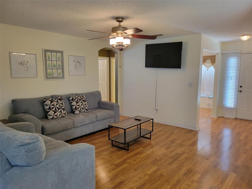 A living room features a grey sofa, a coffee table, and a wall-mounted television — 2160 ADDISON AVENUE, CLERMONT, FL