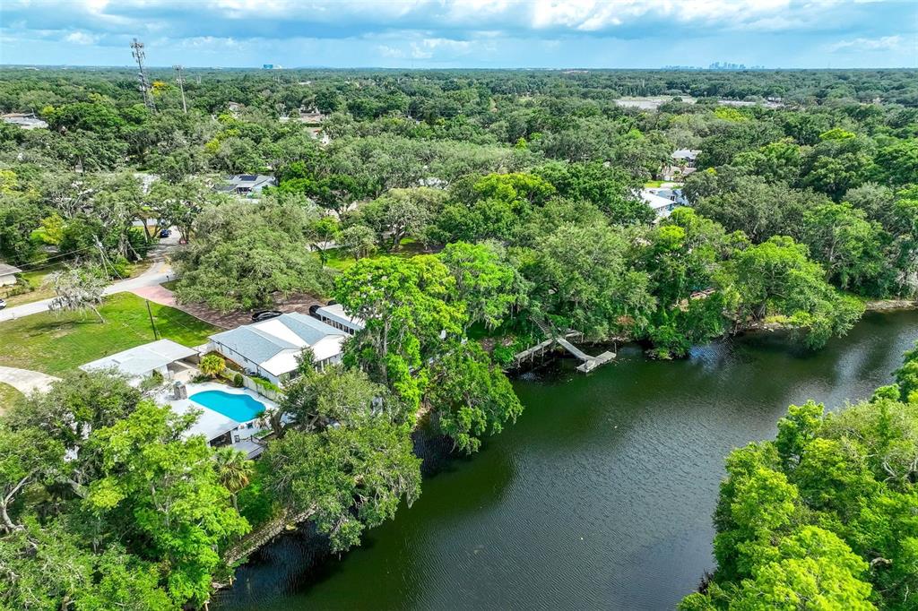 An aerial view shows a house with a swimming pool situated along a riverbank — 11935 RIVERHILLS DRIVE, TAMPA, FL