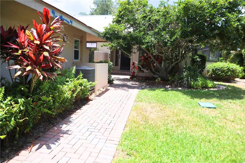 A single-story duplex with a red tile roof and two garage doors faces a driveway — 4820 KESTRAL PARK CIRCLE UNIT 18, SARASOTA, FL