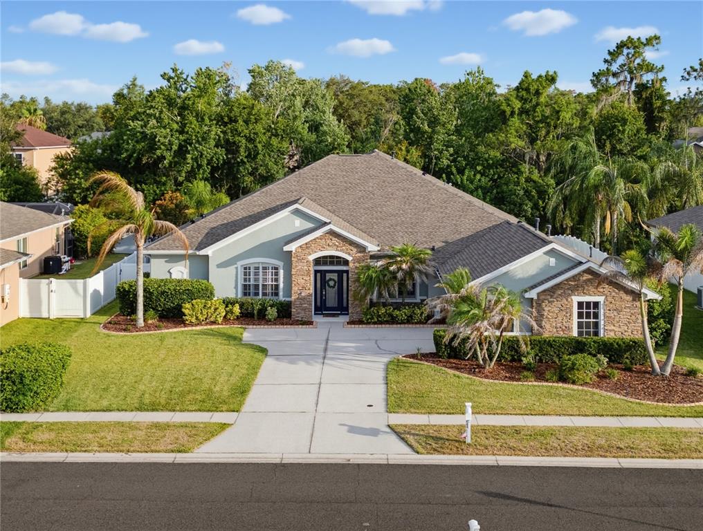 A single-story house with a stone facade, light green siding, and a concrete driveway — 11704 NEWBERRY GROVE LOOP, RIVERVIEW, FL