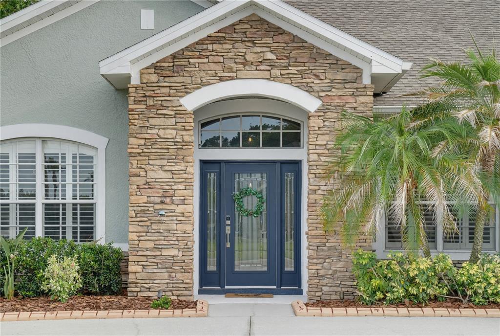 A stone-faced entryway features a dark blue front door with sidelights and a transom window — 11704 NEWBERRY GROVE LOOP, RIVERVIEW, FL