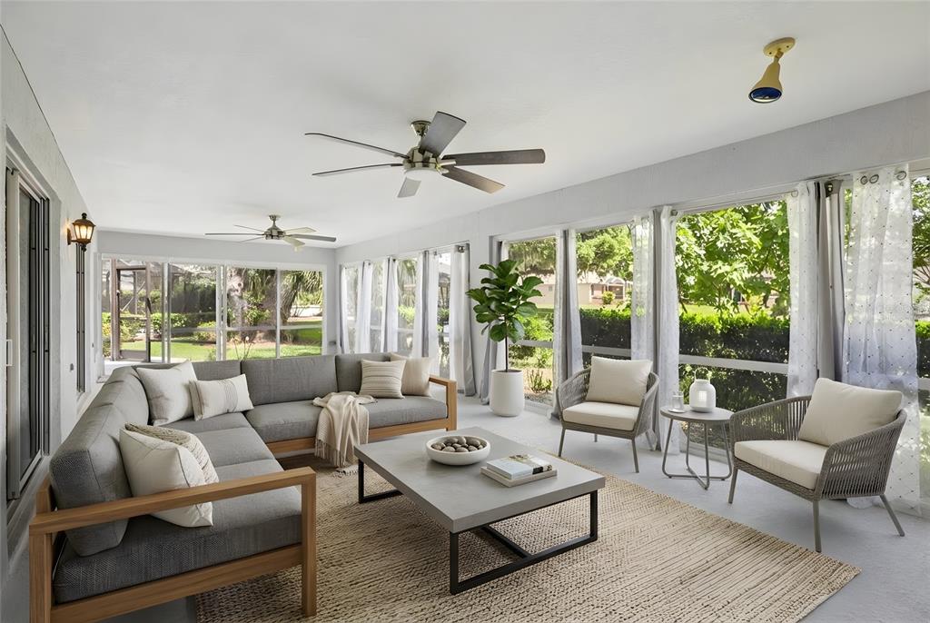 A sunroom features a gray sectional sofa, two armchairs, a coffee table, and ceiling fans — 8690 SE 173RD WISTERIA STREET, THE VILLAGES, FL