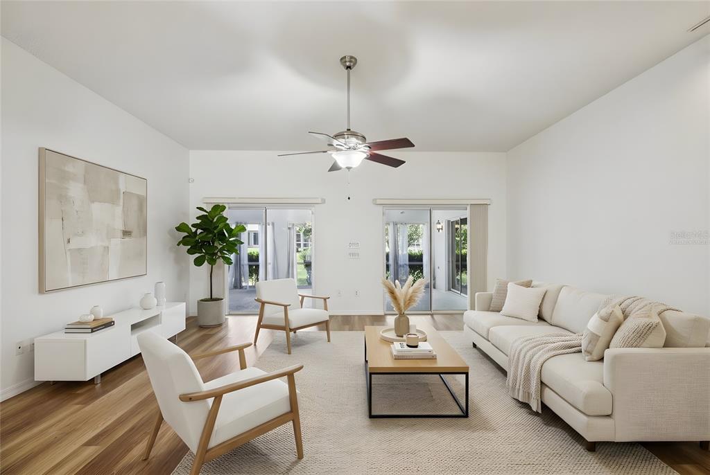 A bright living room features a white sofa, two armchairs, a coffee table, and sliding doors — 8690 SE 173RD WISTERIA STREET, THE VILLAGES, FL