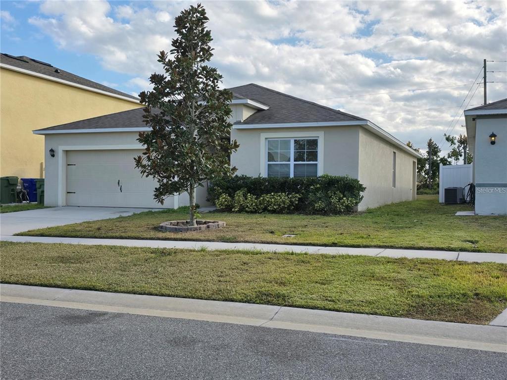 A single-story house with a beige stucco exterior, a two-car garage, and a front yard — 3132 COUNTRY CLUB CIRCLE, WINTER HAVEN, FL