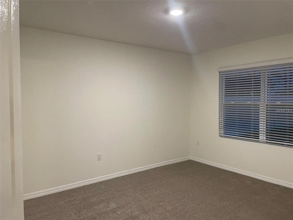 An empty bedroom features beige carpet, white walls, and a window with horizontal blinds — 3132 COUNTRY CLUB CIRCLE, WINTER HAVEN, FL