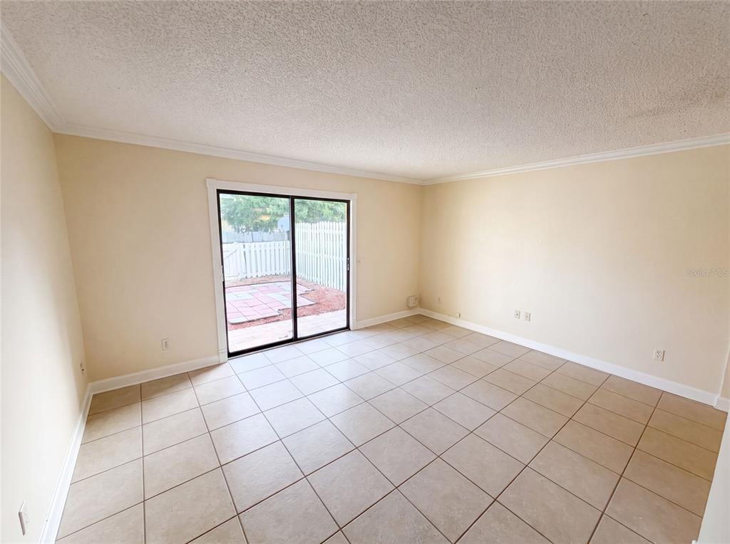 An empty room with beige tile flooring, light-colored walls, and a sliding glass door — 22707 WATERSEDGE BOULEVARD UNIT 53, LAND O LAKES, FL
