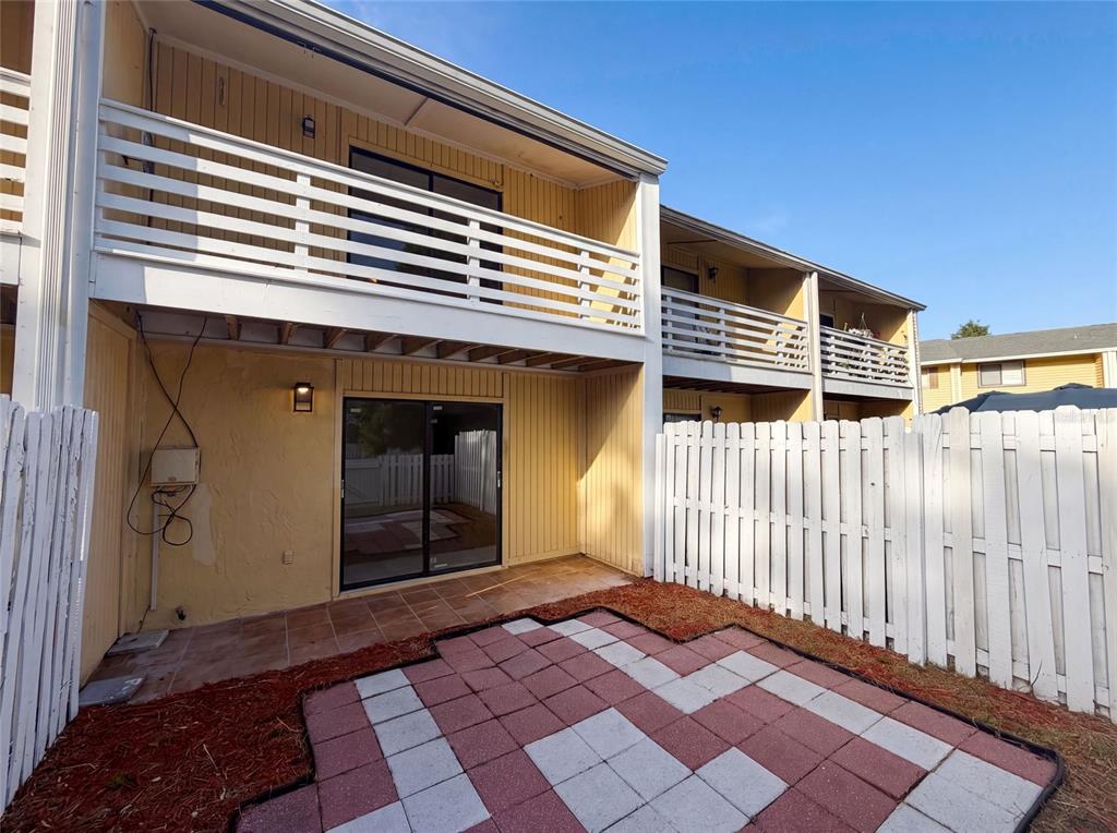 A two-story apartment building features a ground-level patio with pavers and a fenced yard — 22707 WATERSEDGE BOULEVARD UNIT 53, LAND O LAKES, FL