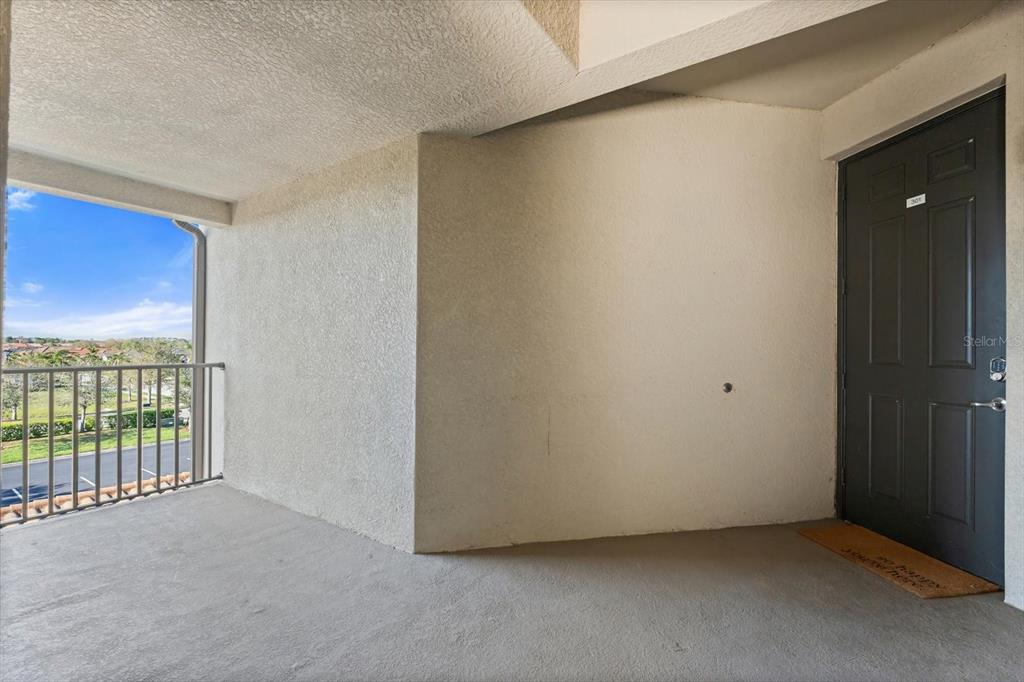 An exterior balcony features a concrete floor, textured walls, and a dark entry door — 16904 VARDON TERRACE UNIT 301, LAKEWOOD RANCH, FL