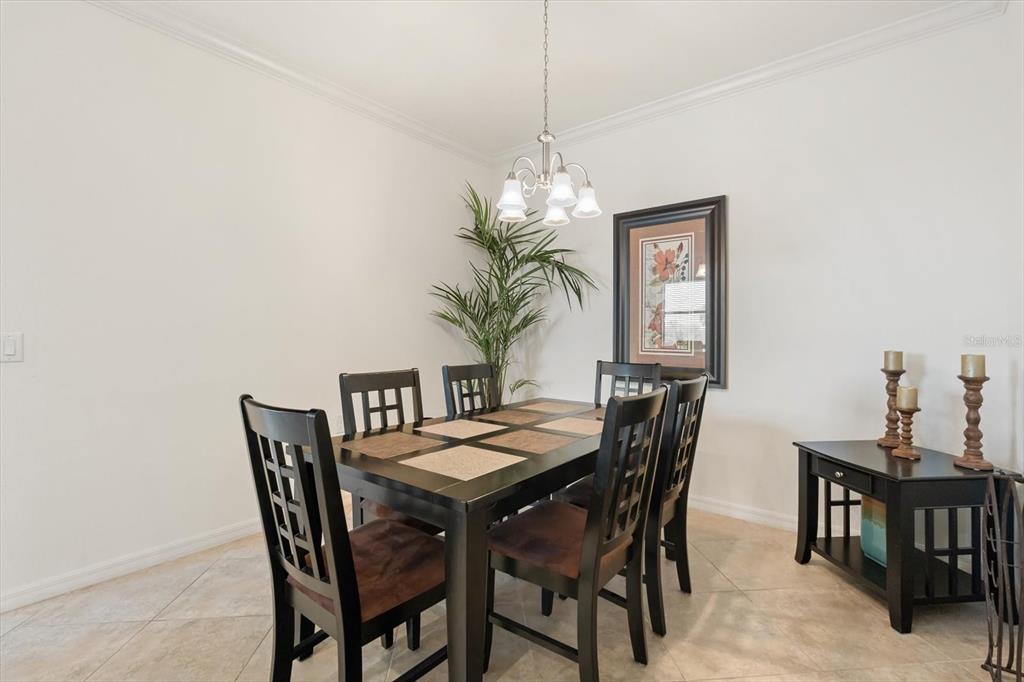 A dining room features a dark wood table with chairs, a chandelier, and a side table — 16904 VARDON TERRACE UNIT 301, LAKEWOOD RANCH, FL