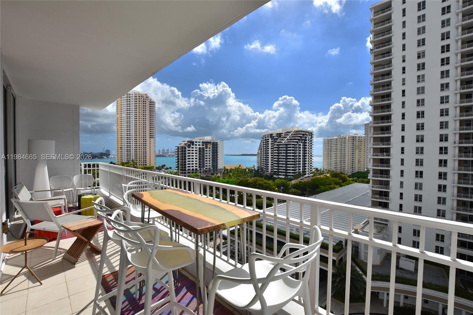 A balcony with outdoor furniture overlooks a city skyline and a body of water — 801 Brickell Key Blvd # 1209, Miami FL 33131, MIAMI, FL