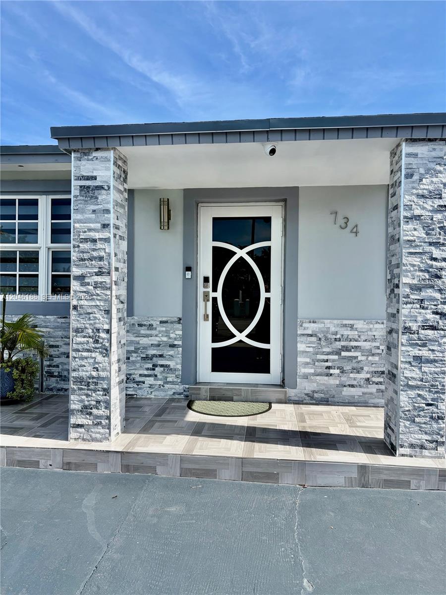 The front entrance features a white door with a circular design, stone pillars, and tiled steps — 734 E 39th St, Hialeah FL 33013, HIALEAH, FL
