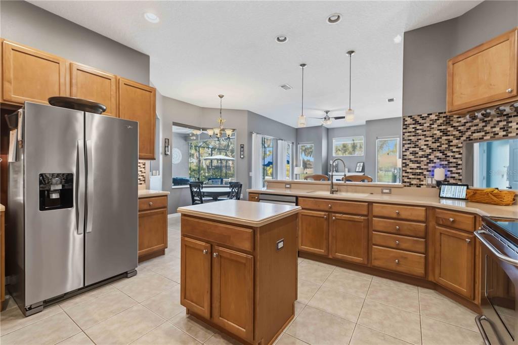 A kitchen with wood cabinets, stainless steel appliances, a center island, and tile flooring — 5723 114TH DRIVE E, PARRISH, FL