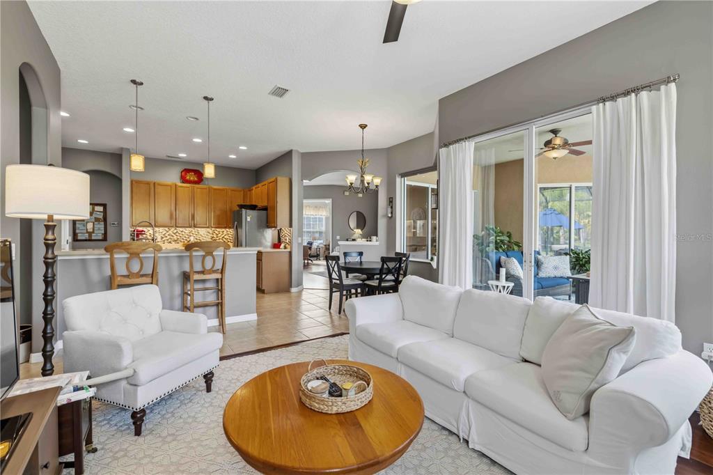 A living room with a white sofa and armchair opens to a kitchen and dining area — 5723 114TH DRIVE E, PARRISH, FL