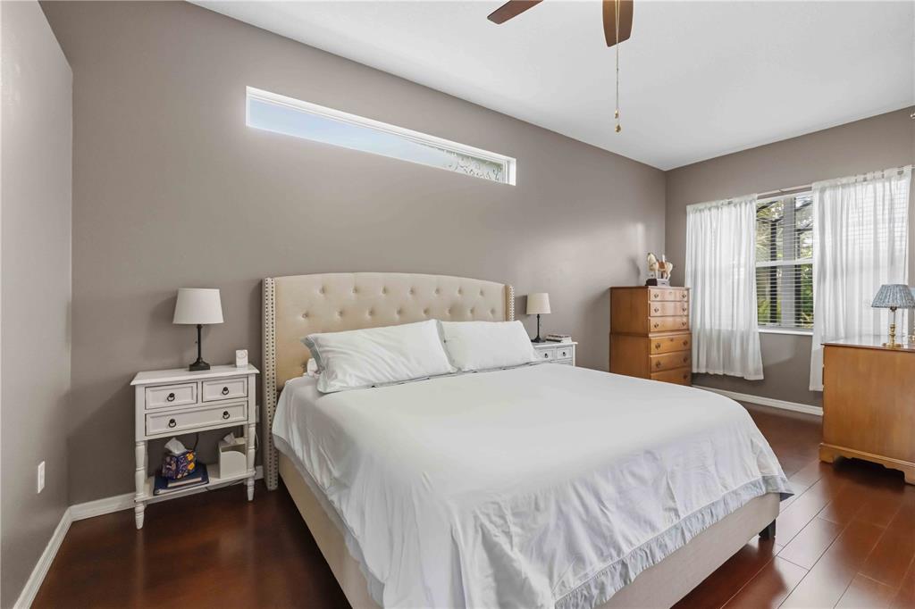 A bedroom features a tufted headboard, white nightstands, a wooden dresser, and a clerestory window — 5723 114TH DRIVE E, PARRISH, FL