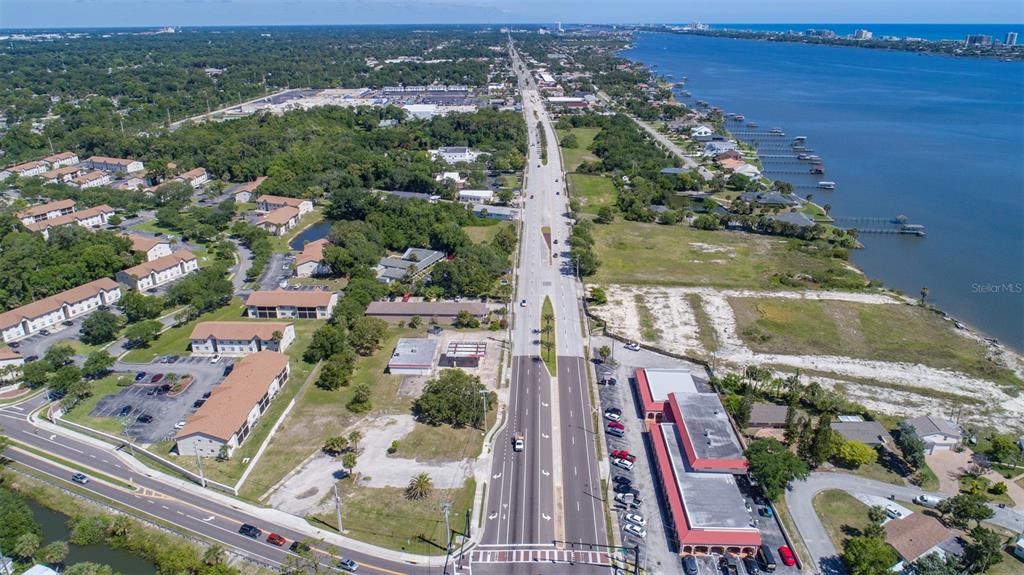 An aerial view shows a multi-lane road running between residential buildings and a waterfront area — 2750 S RIDGEWOOD AVENUE, SOUTH DAYTONA, FL
