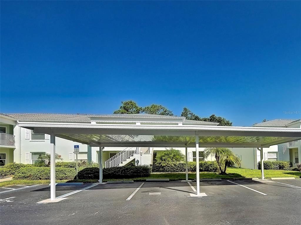 A white metal carport stands in a parking lot in front of a residential building — 5725 GREENWOOD AVENUE UNIT 7104, NORTH PORT, FL