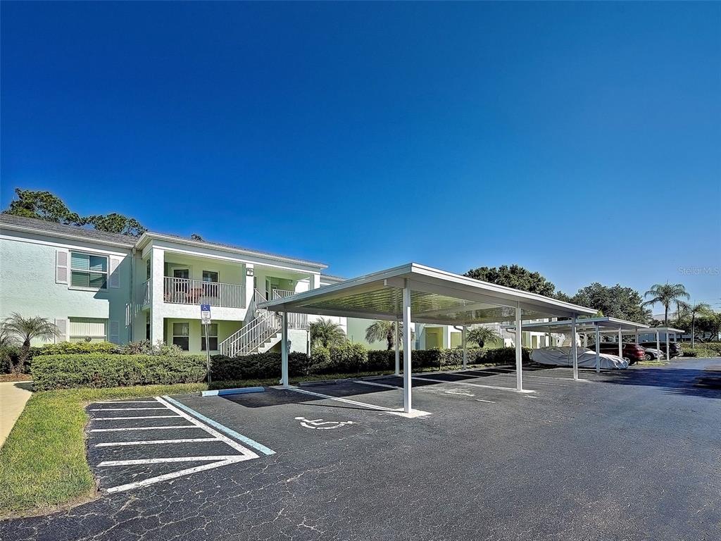 An apartment building exterior with a covered parking area and a handicap-accessible parking space — 5725 GREENWOOD AVENUE UNIT 7104, NORTH PORT, FL