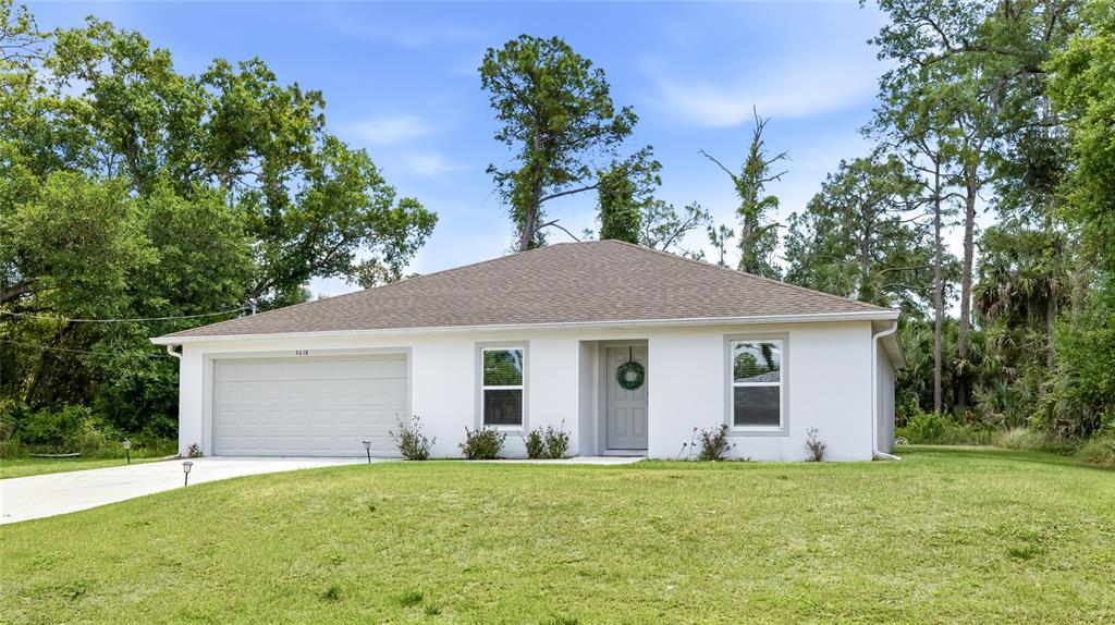 A single-story white house with a two-car garage and a front door with a wreath — 3618 WHITMAN STREET, NORTH PORT, FL