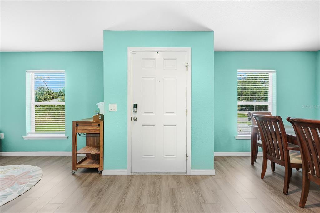 A dining room with light blue walls, wood-look flooring, a white door, and two windows — 3618 WHITMAN STREET, NORTH PORT, FL