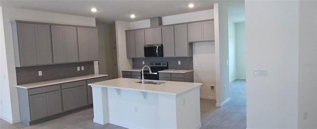 A kitchen features gray cabinets, white countertops, a central island, and stainless steel appliances — 51 KANKAKEE TRAIL, PALM COAST, FL