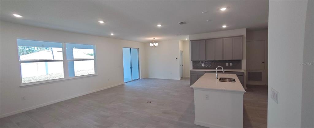 An open-concept kitchen and living area features gray cabinetry, a central island, and tile flooring — 51 KANKAKEE TRAIL, PALM COAST, FL