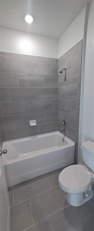 A bathroom features a white bathtub with a grey tiled surround and a white toilet — 51 KANKAKEE TRAIL, PALM COAST, FL