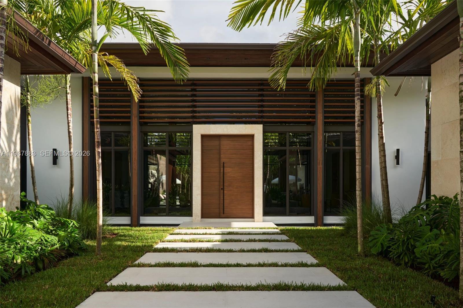 A modern home entrance features a wooden double door, large windows, and a stone walkway — 6371 SW 107th St, Pinecrest FL 33156, PINECREST, FL