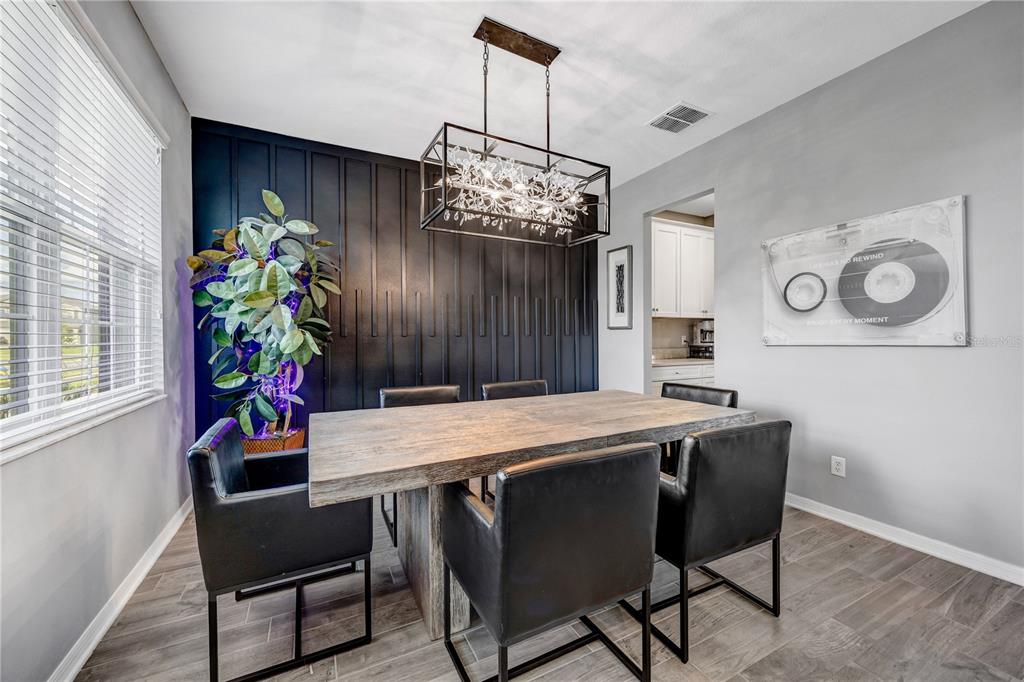 A dining room features a wooden table, black chairs, a dark accent wall, and a chandelier — 32455 SAPNA CHIME DRIVE, WESLEY CHAPEL, FL