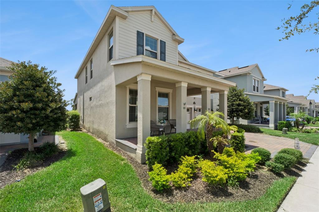 A two-story beige house with a front porch, landscaping, and a paved walkway — 9152 SONOMA COAST DRIVE, WINTER GARDEN, FL