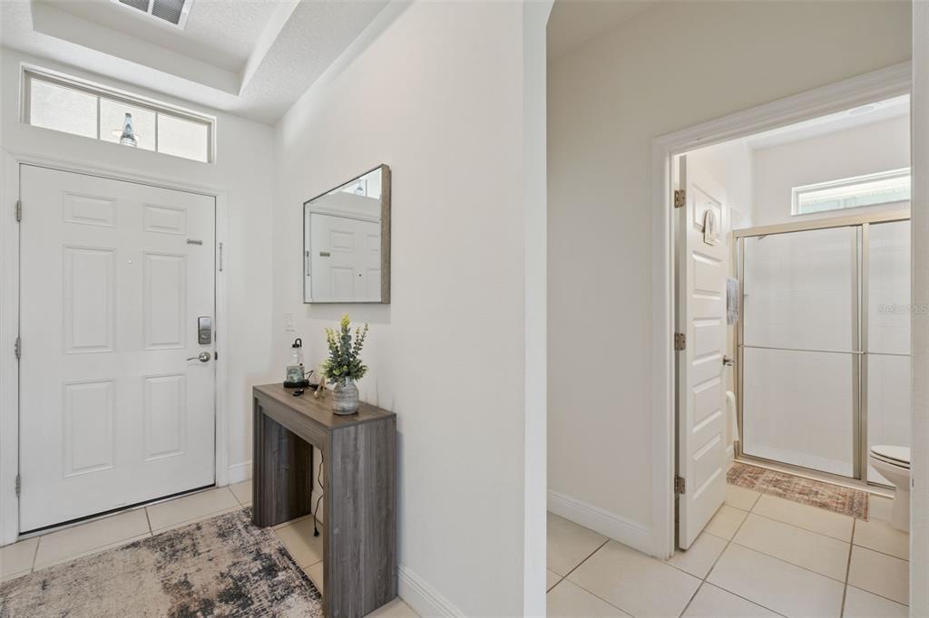 An entryway features a white front door, a console table with a mirror, and a bathroom — 9152 SONOMA COAST DRIVE, WINTER GARDEN, FL