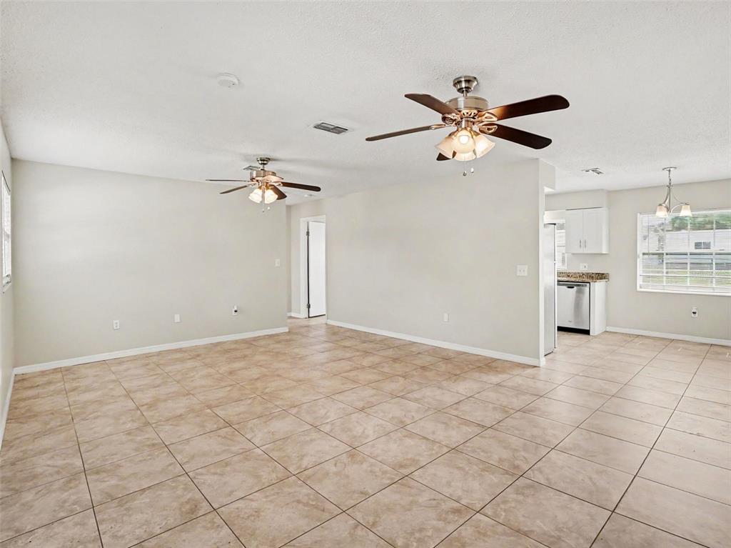 An open-concept living area features light-colored tile flooring, two ceiling fans, and a kitchen — 3255 KELVINGTON DRIVE, ORLANDO, FL