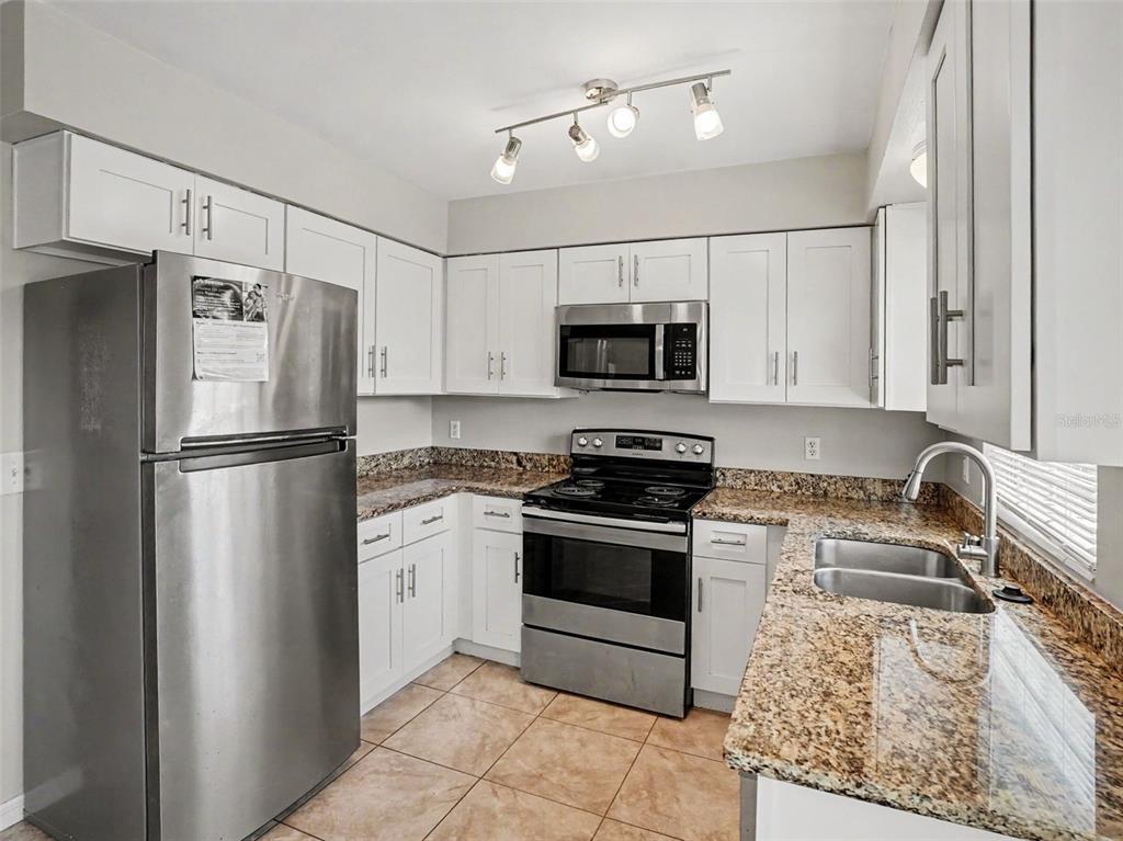 A kitchen with white cabinets, stainless steel appliances, and granite countertops — 3255 KELVINGTON DRIVE, ORLANDO, FL
