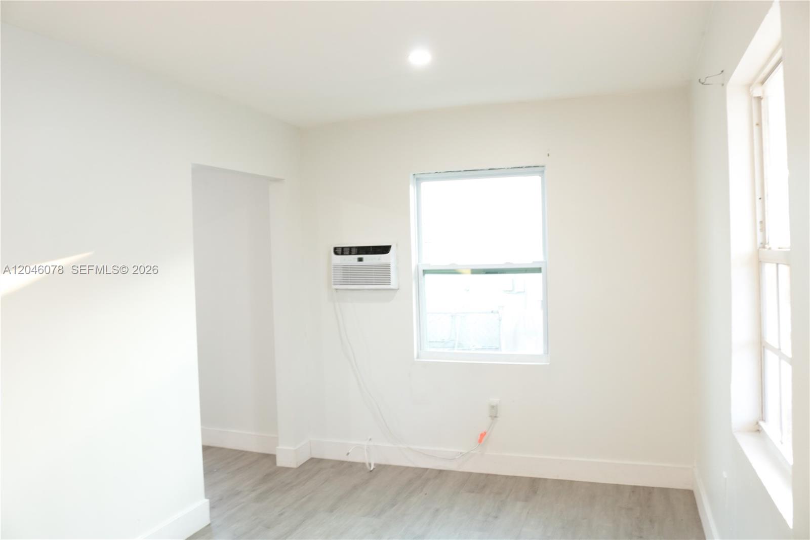 A sparsely furnished room with white walls, light wood flooring, and a window air conditioner — 1768 NW 112th Ter # 1, Miami FL 33167, MIAMI, FL