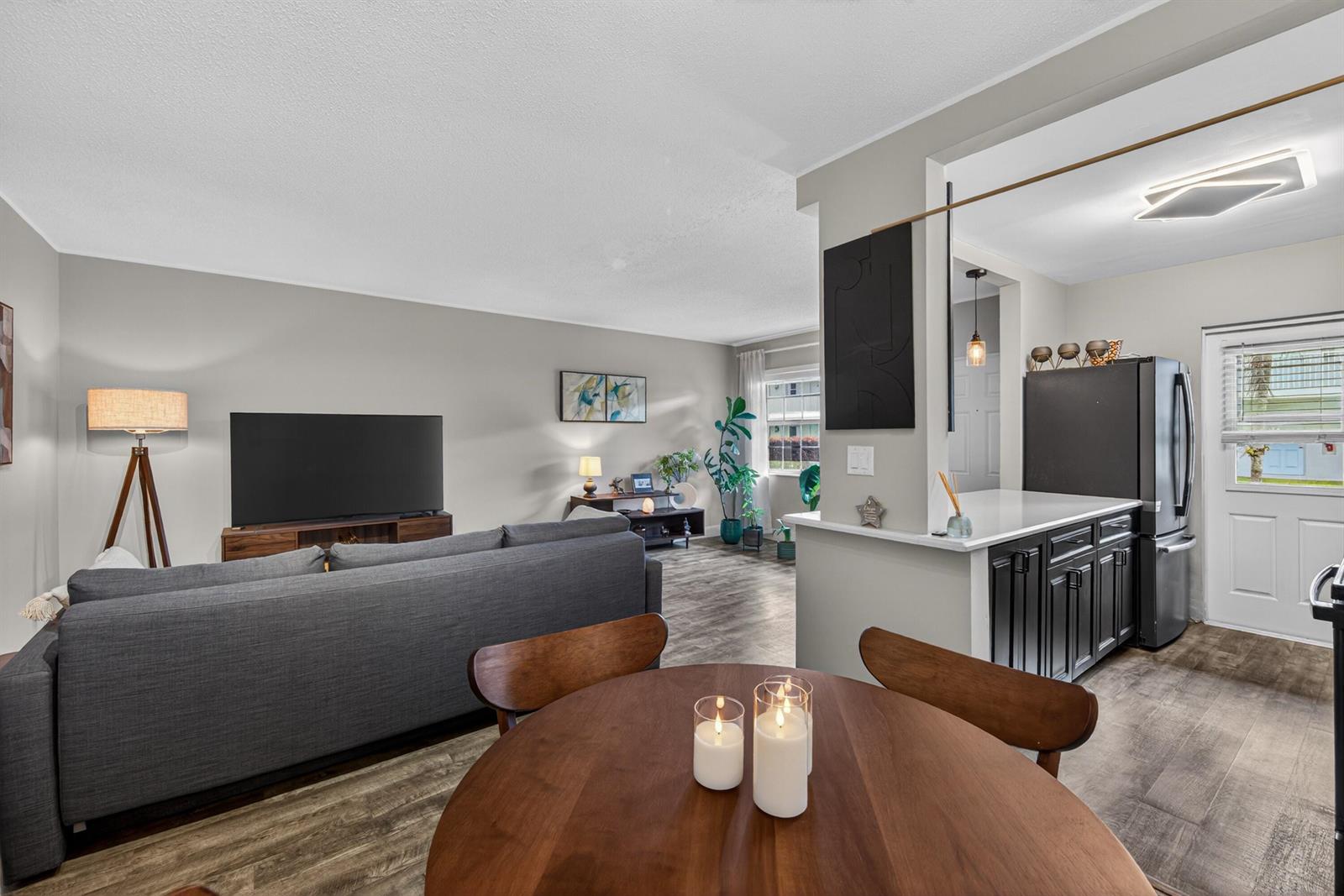 A living room and dining area feature gray walls, wood-look flooring, and a kitchen pass-through — 2110 NE 42nd Street # 4b, Lighthouse Point FL 33064, LIGHTHOUSE POINT, FL