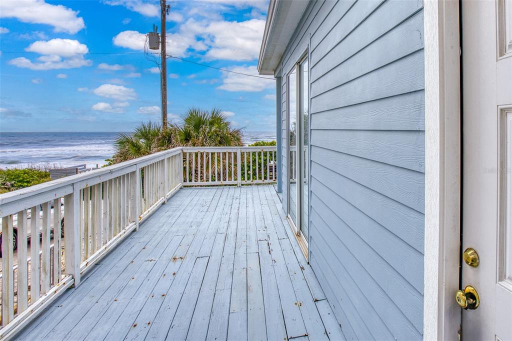 A light blue wooden deck overlooks the ocean with a white railing and sliding glass doors — 6368 S ATLANTIC AVENUE, NEW SMYRNA BEACH, FL