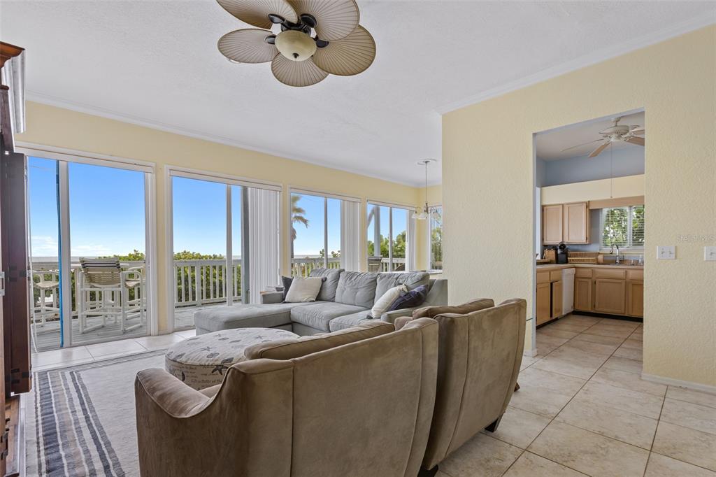 A living room with a sectional sofa, tile floors, and sliding doors leading to a deck — 6368 S ATLANTIC AVENUE, NEW SMYRNA BEACH, FL