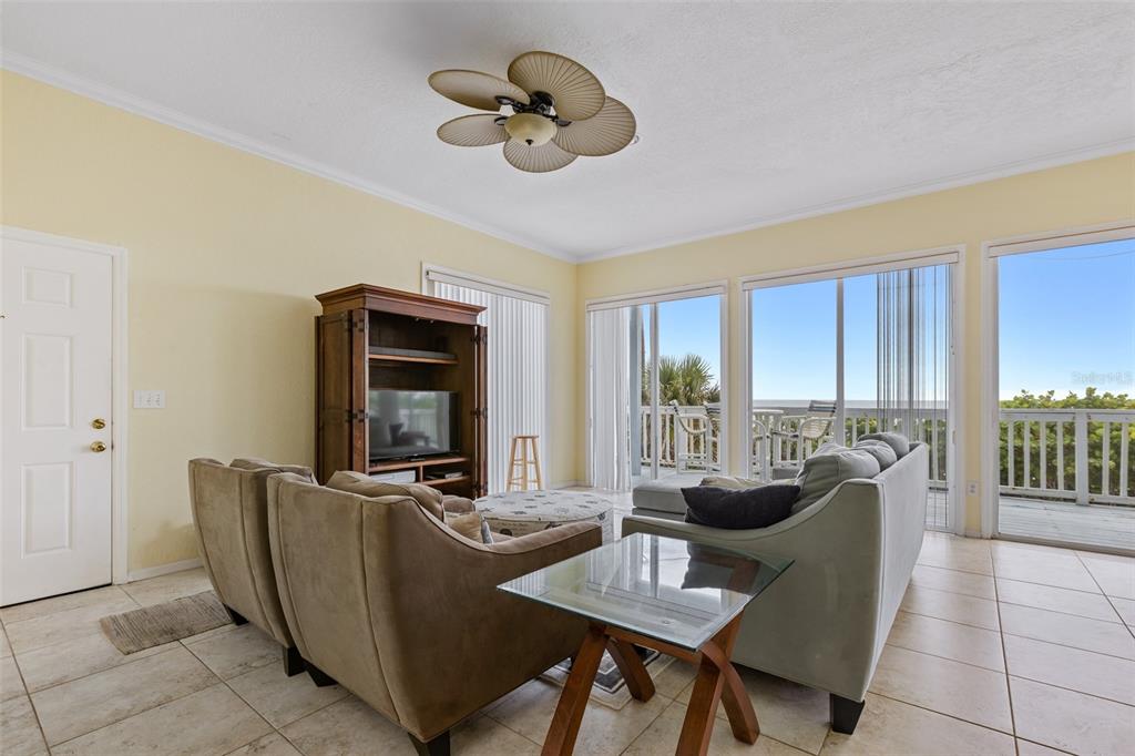 A living room with tile floors, a ceiling fan, and sliding glass doors to a deck — 6368 S ATLANTIC AVENUE, NEW SMYRNA BEACH, FL