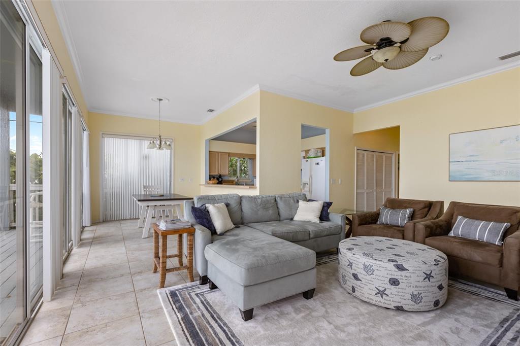 A living room with tile floors, a gray sectional, brown armchairs, and a ceiling fan — 6368 S ATLANTIC AVENUE, NEW SMYRNA BEACH, FL
