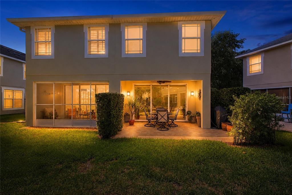 The rear exterior of a two-story house features a screened-in porch and a paved patio — 477 HARBOR RIDGE DRIVE, PALM HARBOR, FL