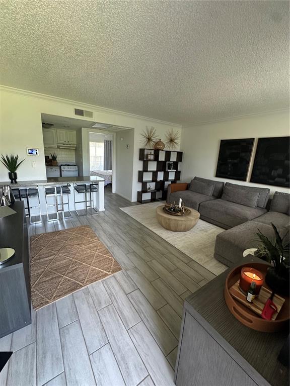 A living room with light wood-look tile floors, a gray sectional, and an open kitchen — 115 OYSTER BAY CIRCLE UNIT 170, ALTAMONTE SPRINGS, FL