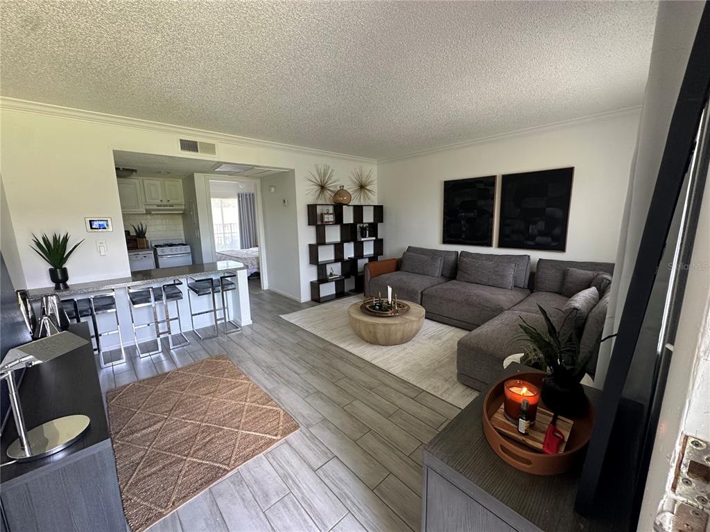 A living room with gray tile floors, a sectional sofa, and an open kitchen area — 115 OYSTER BAY CIRCLE UNIT 170, ALTAMONTE SPRINGS, FL