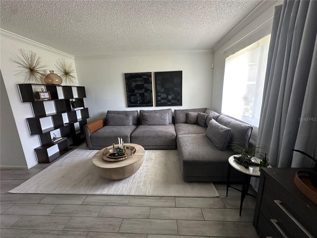 A living room features a large gray sectional sofa, a round coffee table, and shelving — 115 OYSTER BAY CIRCLE UNIT 170, ALTAMONTE SPRINGS, FL
