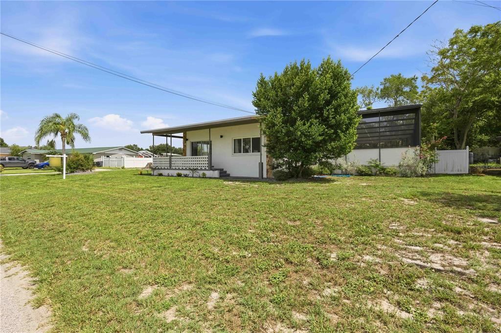 A single-story house with a covered porch and a screened-in patio sits on a lawn — 6704 WINTERSET GARDENS ROAD, WINTER HAVEN, FL