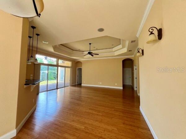 An open-concept living area features a tray ceiling, hardwood floors, and sliding glass patio doors — 8913 SW 74TH AVENUE, GAINESVILLE, FL