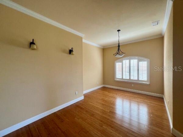 An empty room features hardwood floors, beige walls, two wall sconces, and a window with shutters — 8913 SW 74TH AVENUE, GAINESVILLE, FL