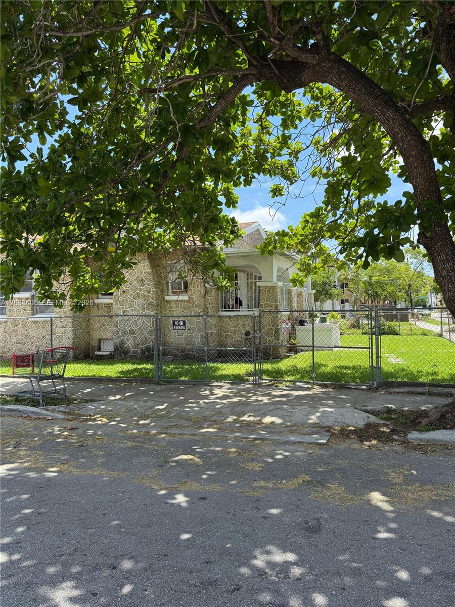 A stone-clad house sits behind a chain-link fence under a large, leafy tree — 1269 NW 4th St, Miami FL 33125, MIAMI, FL