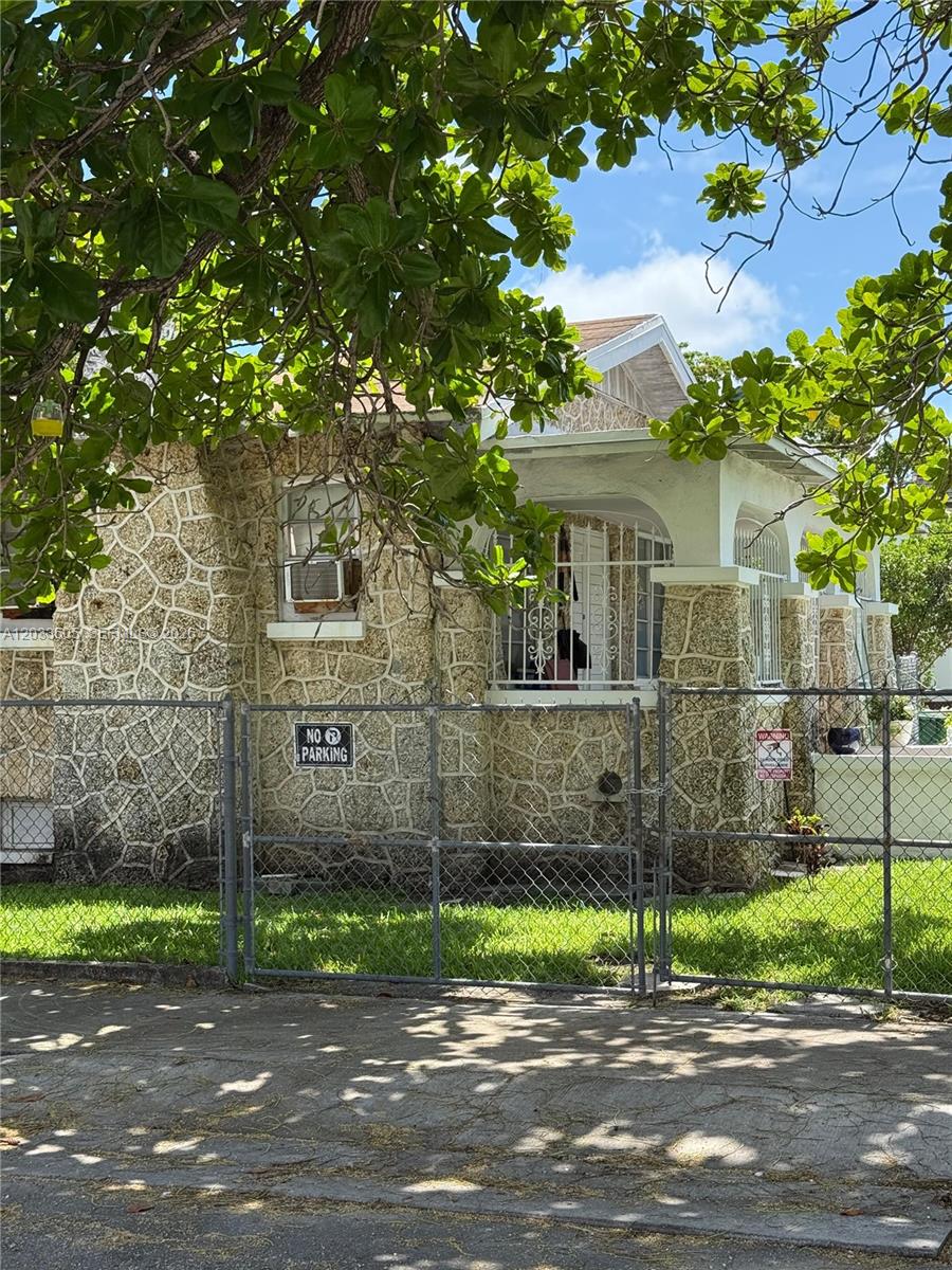 A single-story house with a stone facade and a front porch behind a chain-link fence — 1269 NW 4th St, Miami FL 33125, MIAMI, FL